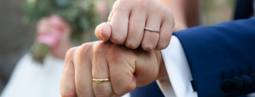 a newlywed couple showing their wedding bands - Estate Planning for Newlyweds