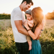 A family is holding a baby in a sunlit field, smiling and enjoying the moment. This image represents the concept of beneficiary designation questions, emphasizing the importance of properly designating beneficiaries to ensure your family's future security and well-being.