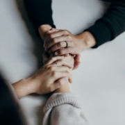 Two people are holding hands solemnly, conveying a sense of support and seriousness. This image relates to the cost to set up a living will, highlighting the importance of making informed decisions about medical treatment preferences and the associated expenses.