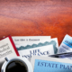 Essential estate planning documents, including life insurance, last will and testament, and 401(k) statement, on a wooden desk with a coffee cup.